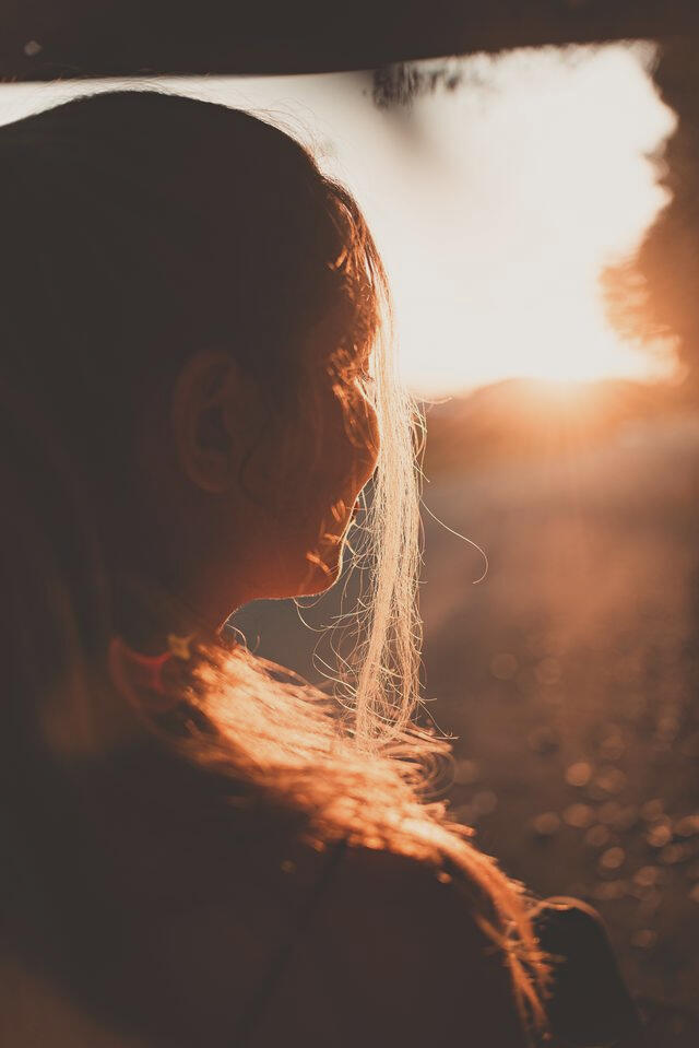 woman with long hair looking at sunset